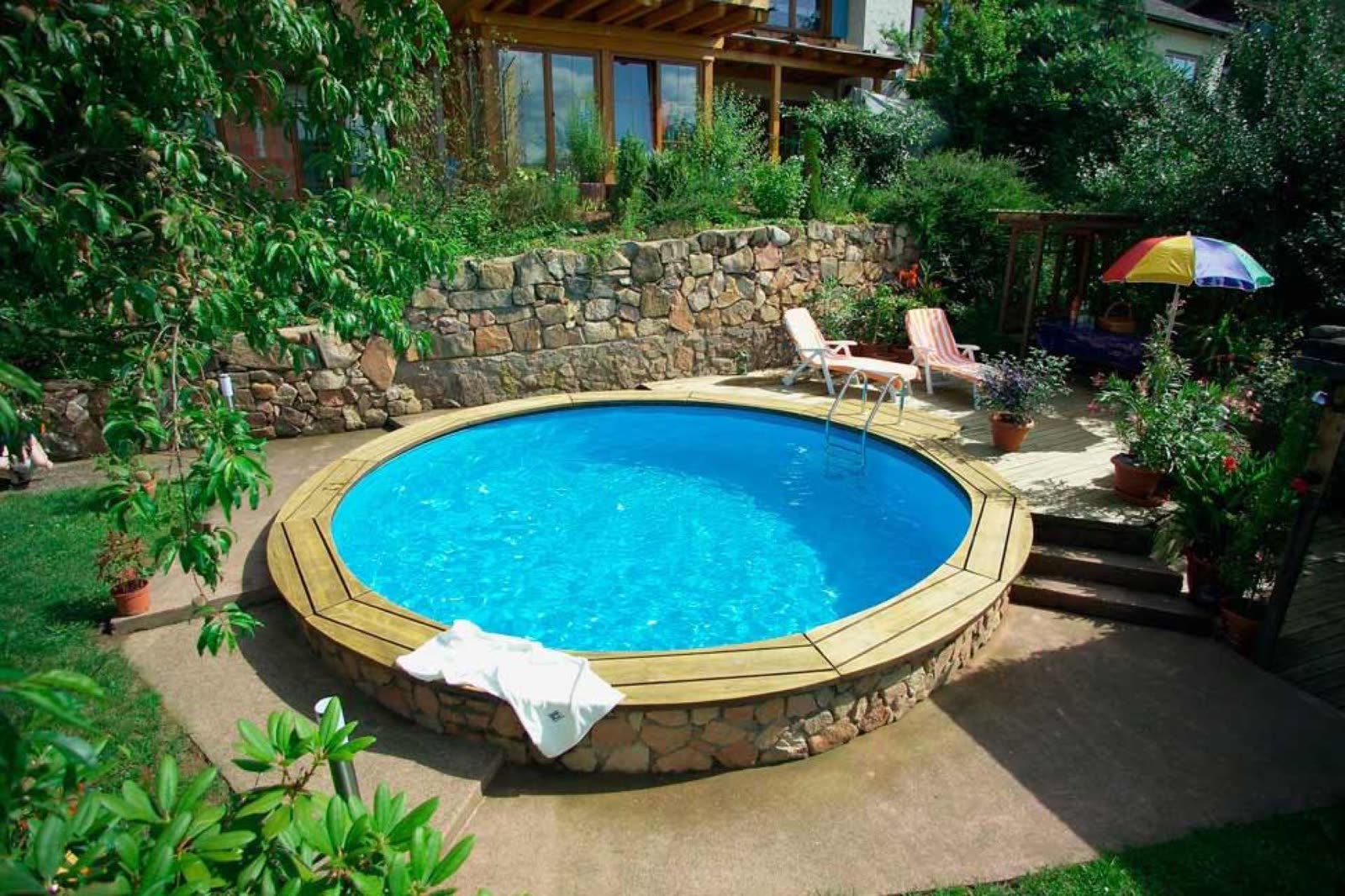 Yuvarlak Bora havuzu, taş duvarla çevrili bahçe terasında